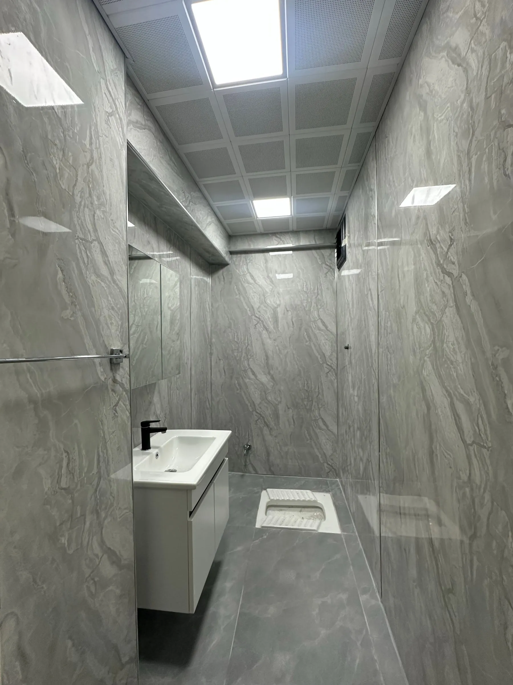 Duvarları PVC mermer plaka ile, zemini büyük ebat seramikle yenilenmiş alaturka tuvalet